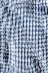 Wavy uneven surface of blue sweater with parallel loops vertical stripes
