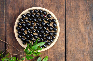 Jabuticaba, Jabuticabas freshly harvested in pots and baskets arranged on rustic wood, top view.