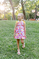 Child girl in a beautiful dress with blue eyes walks in the park