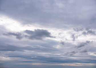 Overcast sky with gray and white clouds, some light shines through the clouds.