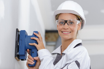 young woman is sanding wall