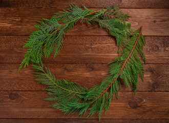 Christmas composition. Wreath made of christmas tree branches, on dark wooden  background. Christmas, winter concept. Flat lay, top view.