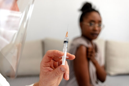 Immunization against covid-19 and flu, antivirus procedure, professional care and treat from virus. Caucasian doctor in protective mask make vaccination to African american female patient, cropped.