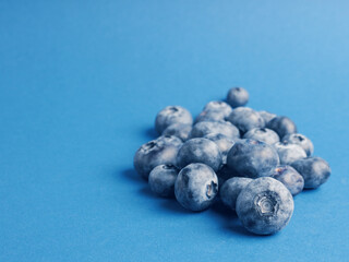 A heap of blueberries on a blue backgrond with space for text, super food or healthy eating, fresh organic food