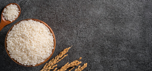 White rice in a bowl on dark black table background.