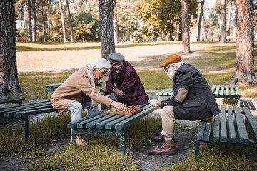 Multicultural senior men playing chess in park