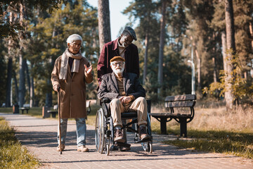 Asian man talking near interracial friends with wheelchair in autumn park