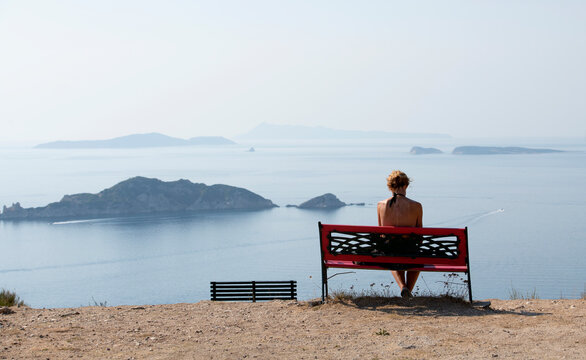 Rear view of a woman sitting on a bench near Porto Timoni beach, Afionas, Corfu, Greece