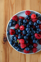 Delicious juicy ripe wild berries raspberries and blueberries in colorant. Washed berries for breakfast
