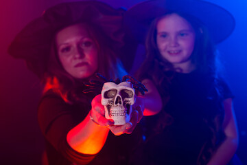 Two halloween witches making magic with scull in halloween night. Magic, holidays and mystic concept.