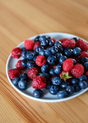 Delicious juicy ripe wild berries raspberries and blueberries in colorant. Washed berries for breakfast
