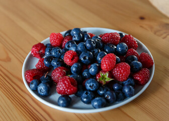 Delicious juicy ripe wild berries raspberries and blueberries in colorant. Washed berries for breakfast