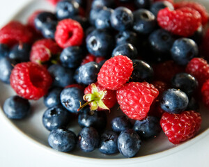 Delicious juicy ripe wild berries raspberries and blueberries in colorant. Washed berries for breakfast