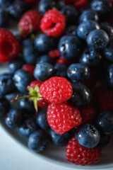 Delicious juicy ripe wild berries raspberries and blueberries in colorant. Washed berries for breakfast