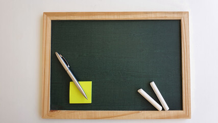 An old blackboard with chalk, pen and notepad.