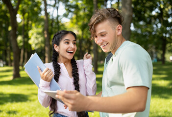 After exam. Excited international students friends celebrating successful test pass, looking at textbook and smiling