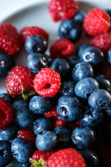 Delicious juicy ripe wild berries raspberries and blueberries in colorant. Washed berries for breakfast
