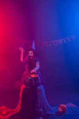 Fototapeta premium Little witch child cooking potion in the cauldron on Halloween.