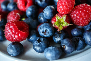 Delicious juicy ripe wild berries raspberries and blueberries in colorant. Washed berries for breakfast