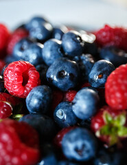 Delicious juicy ripe wild berries raspberries and blueberries in colorant. Washed berries for breakfast