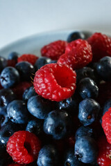 Delicious juicy ripe wild berries raspberries and blueberries in colorant. Washed berries for breakfast