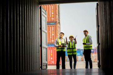 Team engineer dock control logistics worker wear safety helmets and protect suite open cargo container door and working and checking product with taplets.
