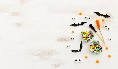 top view image of Halloween holoday. witcher broom, treats and bats over white wooden table