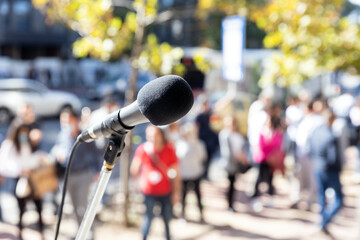 Naklejka premium Vox populi concept. Focus on microphone, blurred group of people in the background.