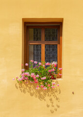 Fototapeta na wymiar Window on a yellow stone building with decorative flowers.