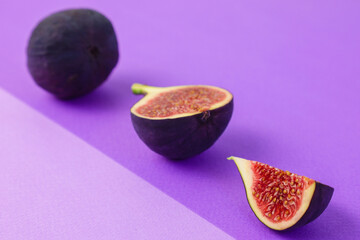ripe figs and slice of fig on violet and purpure asemetric background, copy space