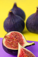 fresh figs on a purple and yellow paper background, vertical