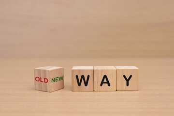wooden cube with text OLD WAY and NEW WAY on a wooden table
