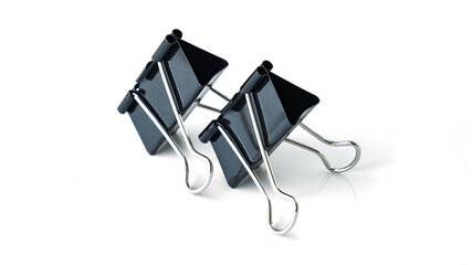 Two big black binder clips for paper isolated. Isolated binder clips. Binder clips for paper on a white background. Black papers clip isolated on white.