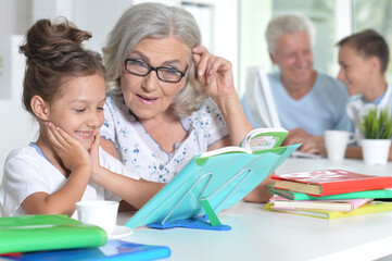 Fototapeta premium Grandmother with cute little girl doing homework together