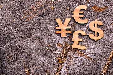International currency units on wooden background. Wooden economy and currency unit on a grey background. Euro, british pound, dollar and yen symbols.