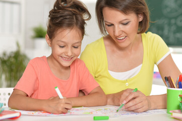 little cute girl with mother drawing at the table