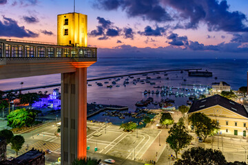 Lacerda elevator illuminated at dusk and with the sea and boats in the background in the city of Salvador, Bahia - obrazy, fototapety, plakaty