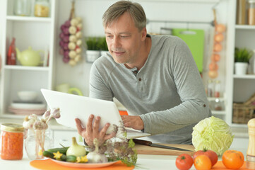 Portrait of elderly male chef using laptop
