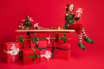 Portrait of funky attractive cheerful elf making holding gift dream sitting on table winter season...