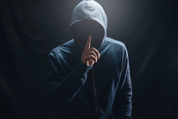 the hacker in the hood makes a silence gesture - obrazy, fototapety, plakaty