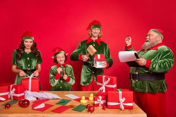 Portrait of four trendy cheerful elfs santa helper preparing gift list order isolated over bright...