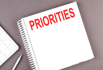 PRIORITIES text on the notebook with calculator and pen