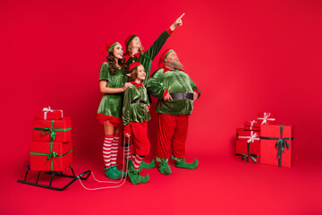 Full size photo of santa helpers people point look empty space with sled giftboxes wear new year...