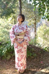 森林を背景に浴衣を着た若い笑顔の女性	