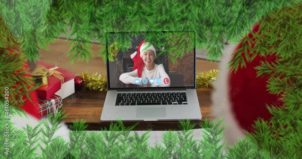 Poster Green branches over father and son wearing santa hats having a videocall on laptop during christmas