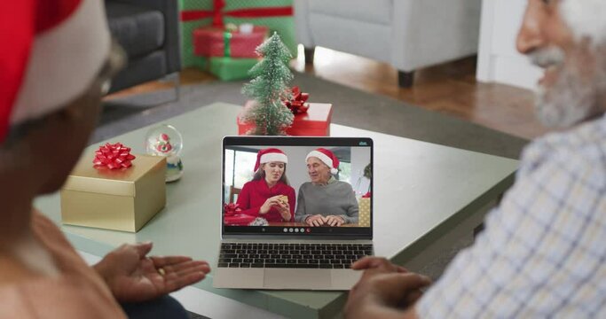 Happy senior african american couple on video call with male friend and daughter at christmas