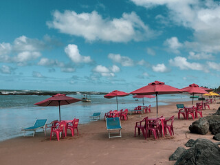 Dia de sol com c&eacute;u azul , nuvens e sombreiros  onde se repete um padr&atilde;o de cores 