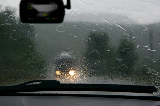 View on road and oncoming traffic in rain through windscreen of moving car