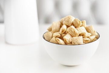 Dry breakfast cereal pads with milk on a light table. selective focus