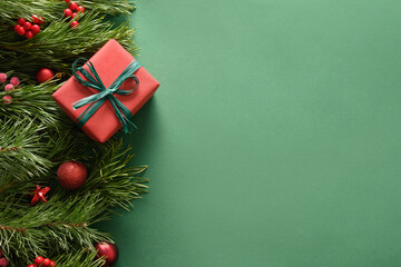 Christmas border with red gift and balls on festive green background. Xmas holiday banner. Top view. New 2022 Year greeting card.